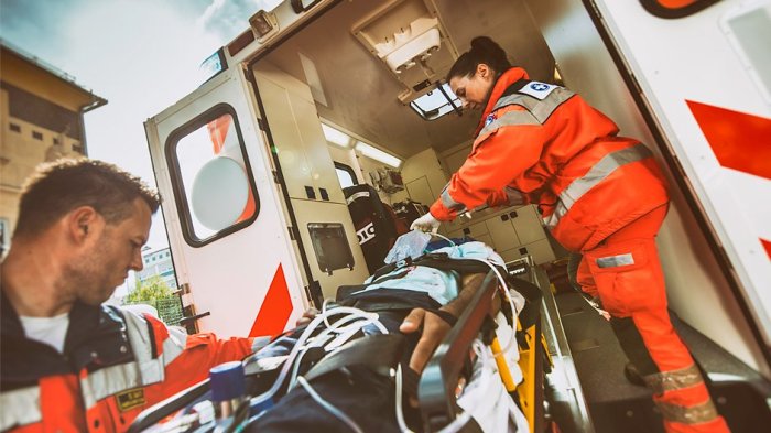 An emergency medical technician is examining a trauma victim