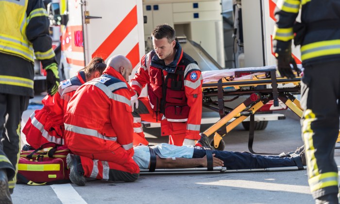 An emergency medical technician is examining a trauma victim